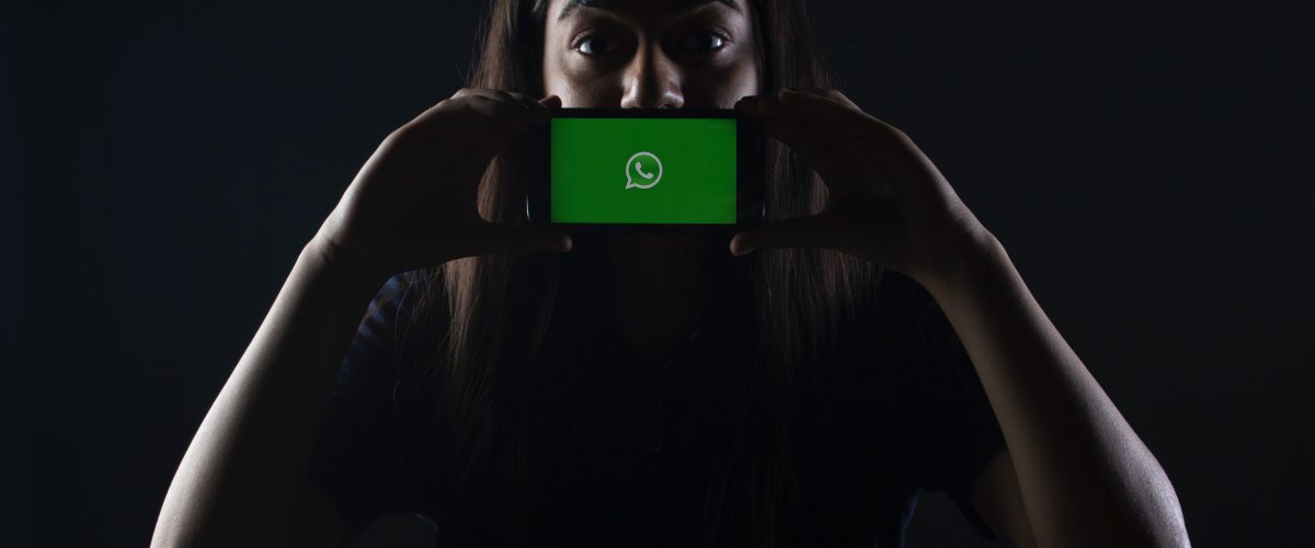 Woman holds mobile device featuring WhatsApp logo