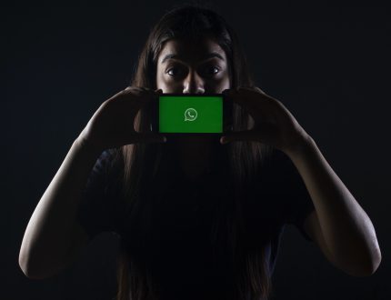 Woman holds mobile device featuring WhatsApp logo