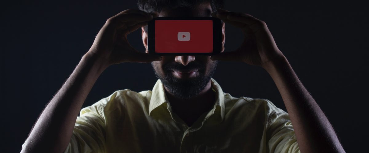 man holding screen displaying YouTube logo
